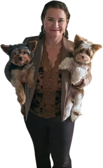 Person holding two small dogs, one in each arm, against a plain background.
